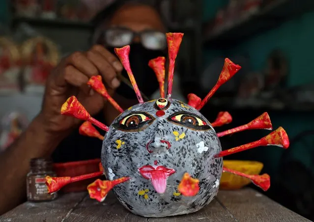 An artisan applies finishing touches to a replica of the coronavirus made from clay at a workshop during a nationwide lockdown to slow the spreading of the coronavirus disease (COVID-19) in Kolkata, April 23, 2020. (Photo by Rupak De Chowdhuri/Reuters)