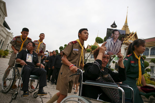 Mourners hold up pictures of Thailand's late King Bhumibol Adulayadej as they are pushed into the Throne Hall at the Grand Palace for the first time to pay respects to his body that is kept in a golden urn in Bangkok, Thailand, October 29, 2016. (Photo by Athit Perawongmetha/Reuters)
