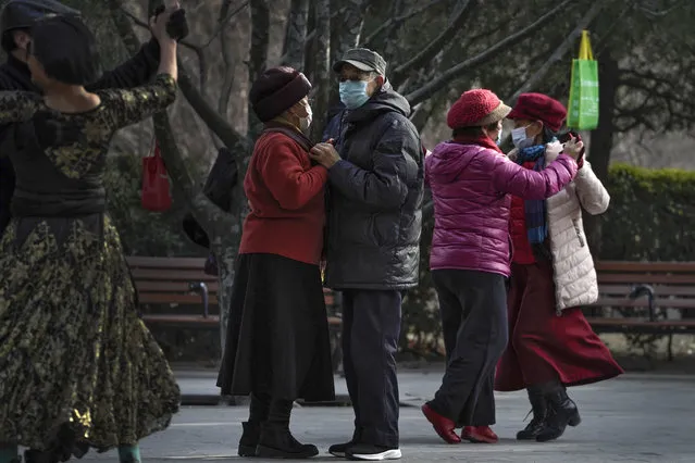People wearing face masks to help curb the spread of the coronavirus enjoy a social dance at a public park in Beijing, Tuesday, January 12, 2021. Lockdowns have been expanded and a major political conference postponed in a province next to Beijing that is the scene of China's most serious recent COVID-19 outbreak. (Photo by Andy Wong/AP Photo)
