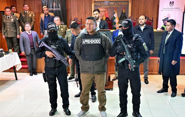 Bolivian Government Minister Eduardo del Castillo (C-back) shows detainee Vladimir Lupa Salamanca (C), head of an elite unit of the Bolivian Armed Forces, during a press conference at the headquarters of the Police General Command in La Paz on July 3, 2024. Lupa is accused of ordering the deployment of 19 snipers to support the failed military coup of June 26. (Photo by Aizar Raldes/AFP Photo)