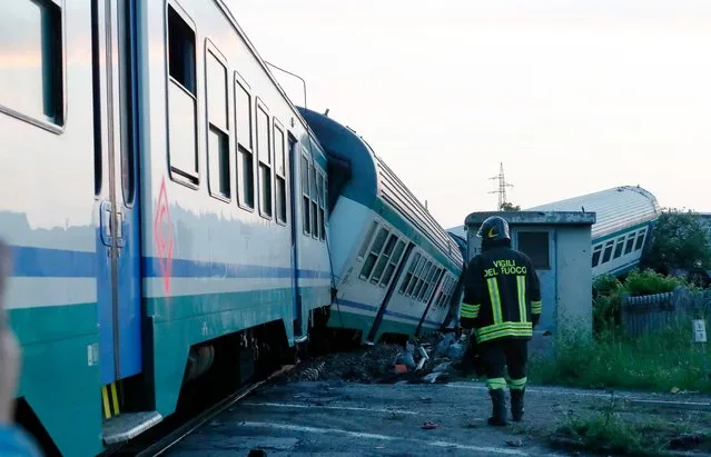 A fireman walks beside the twisted wreckage of a train that plowed into a big-rig truck in Caluso, outside Turin, Italy, early Thursday, May 24, 2018. (Photo by Antonio Calanni/AP Photo)