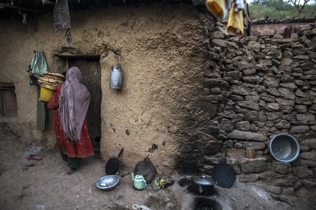 A woman, whose family moved to Islamabad from Pakistan's Khyber-Pakhtunkhwa province to look for work, carries a pile of bread as she enters her house on the outskirts of Islamabad January 1, 2015. (Photo by Zohra Bensemra/Reuters)