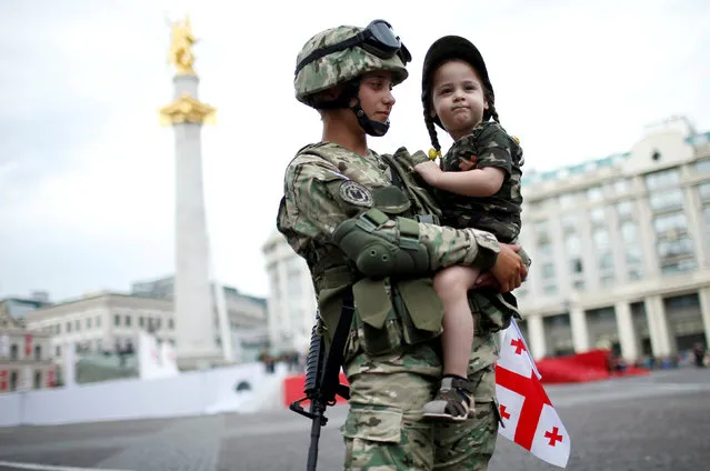Servicewoman, Tamar Kurkumuli, 25, holds her 3-year-old daughter Nino, before the oath-taking ceremony as Georgia marks the 100th anniversary of its independence in Tbilisi, Georgia, May 26, 2018. (Photo by David Mdzinarishvili/Reuters)