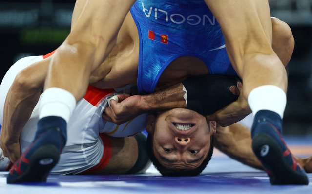 Puerto Rico's Sebastian C Rivera (red) wrestles Mongolia's Tulga Tumur Ochir (blue) in their men's freestyle 65kg wrestling bronze medal match at the Champ-de-Mars Arena during the Paris 2024 Olympic Games, in Paris on August 11, 2024.. (Photo by Kai Pfaffenbach/Reuters)