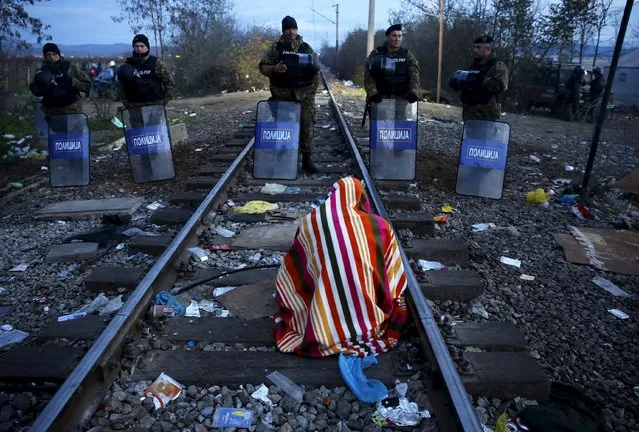 Stranded Iranian migrant Hamid, 34, an electrical engineer from the town of Sanandij, sits on rail tracks in front of Macedonian riot police guarding the border between Greece and Macedonia near the Greek village of Idomeni November 23, 2015. (Photo by Yannis Behrakis/Reuters)