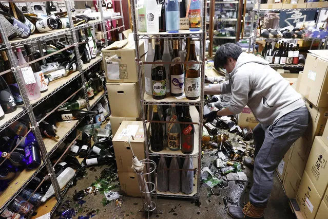 A liquor shop's manager clears the damaged bottles following an earthquake in Fukushima, northeastern Japan Saturday, February 13, 2021. The Japan Meteorological Agency says a strong earthquake has hit off the coast of northeastern Japan, shaking Fukushima, Miyagi and other areas. (Photo by Jun Hirata/Kyodo News via AP Photo)