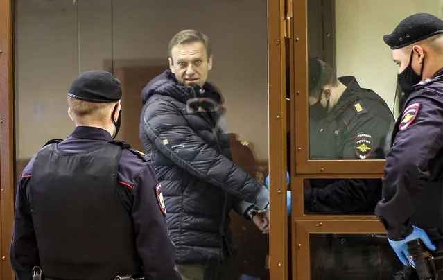 In this photo taken from a footage provided by the Babuskinsky District Court Tuesday, February 16, 2021, Russian opposition leader Alexei Navalny, center, enters a cage to attend a hearing on his charges for defamation in the Babuskinsky District Court in Moscow, Russia. Navalny is accused of defaming a World War II veteran who was featured in a video last year advertising constitutional amendments that allowed an extension of President Vladimir Putin's rule. (Photo by Babuskinsky District Court Press Service via AP Photo)