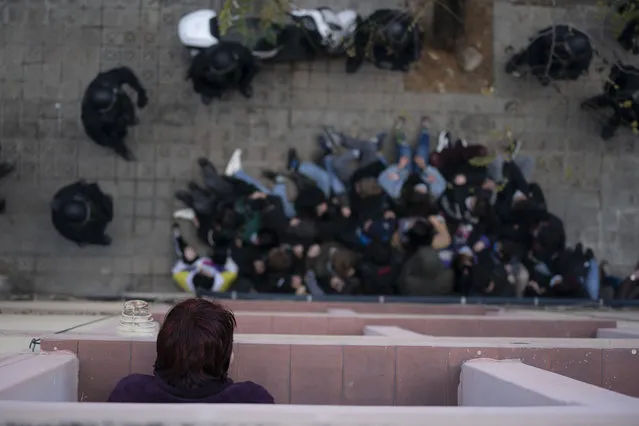 A woman looks from her window at police officers surround activists who try to stop the eviction of Alejandro Ibañez Maltes, 30, from his apartment in Barcelona, Spain, Thursday, December 10, 2020. Alejandro has been accused of not making rent payments and not renewing his lease since February of 2020. (Photo by Joan Mateu/AP Photo)