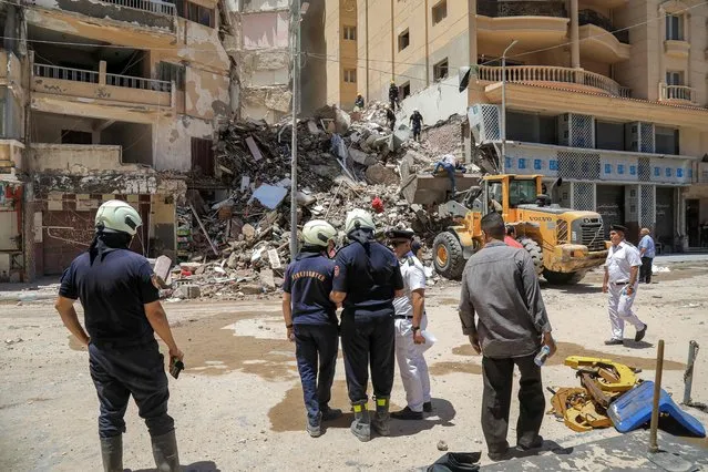 Civil defence first responders speak with a policeman (white) at the scene of a collapsed 13-storey-building in the Sidi Bishr district of Egypt's northern city of Alexandria on June 26, 2023. (Photo by Hazem Gouda/AFP Photo)