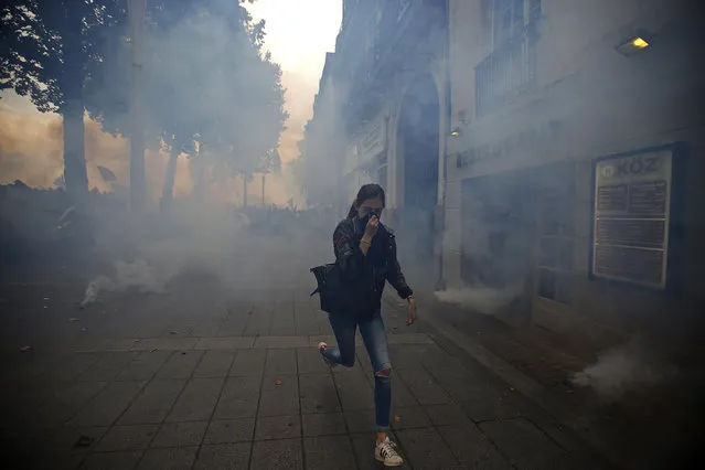 A woman runs away from tear gas during clashes with French riot police at a march in Nantes, western France, to demonstrate against the new French labour law, September 15, 2016. (Photo by Stephane Mahe/Reuters)