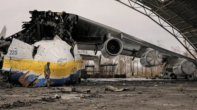 A Ukrainian serviceman walks by an Antonov An-225 Mriya aircraft destroyed during fighting between Russian and Ukrainian forces on the Antonov airport in Hostomel, Ukraine, Saturday, April 2, 2022. At the entrance to Antonov Airport in Hostomel Ukrainian troops manned their positions, a sign they are in full control of the runway that Russia tried to storm in the first days of the war. (Photo by Vadim Ghirda/AP Photo)