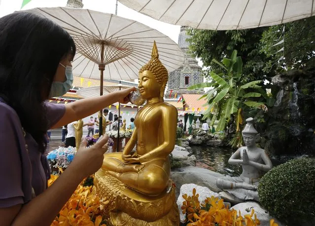 A woman pours traditional scented water over a Buddha statue to mark the Songkran (Thai New Year) celebrations at Wat Pho temple in Bangkok, Thailand, 13 April 2021. Thailand celebrates the traditional new year Songkran festival, also known as water festival, with most events being cancelled following a sudden spike in COVID-19 cases. (Photo by Narong Sangnak/EPA/EFE)