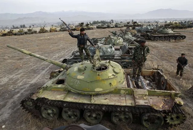 Afghan security forces pose for picture on the top of destroyed Soviet military tank at a junkyard in Jalalabad province February 15, 2015. (Photo by Reuters/Parwiz)