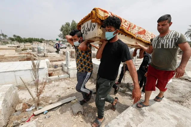 Mourners carry the coffin of a man, who was killed in a fire at a hospital that had been equipped to house coronavirus disease (COVID-19) patients, before burial at a cemetery in Baghdad, Iraq, April 25, 2021. (Photo by Thaier Al-Sudani/Reuters)