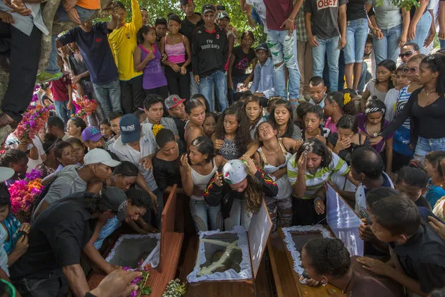 In this November 13, 2016 photo, relatives of nine men from a fishing family, who were shot in the head while on their knees, mourn them at the cemetery in Cariaco, Sucre state, Venezuela. Five law enforcement officers were charged with storming the village and killing these men, who were widely thought to have belonged to a gang. (Photo by Rodrigo Abd/AP Photo)