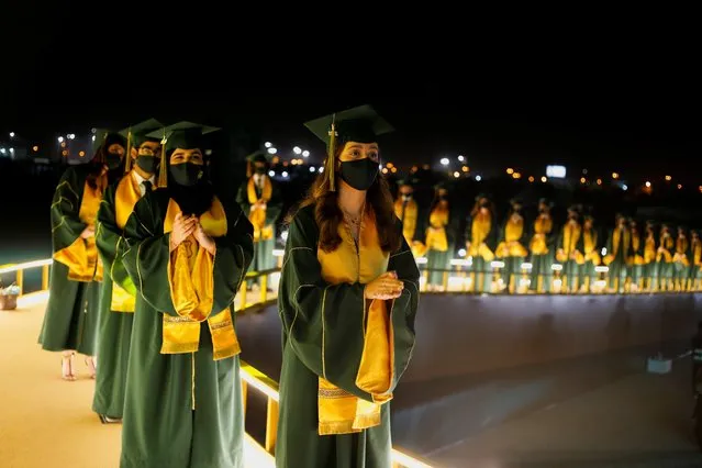 Students wearing face masks and maintaining social distance line up to receive their certificates during The Visual Graduation Ceremony 2021 of Bahrain Bayan School at Bahrain International Circuit parking lot, in Sakhir, Bahrain, May 23, 2021. (Photo by Hamad I Mohammed/Reuters)
