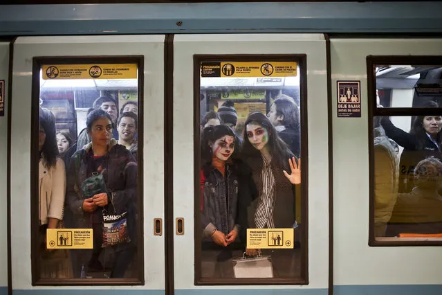 Young women, with their faces painted as a clown and zombie for Halloween, travel in the subway in Santiago, Chile, Tuesday, October 30, 2018. (Photo by Esteban Felix/AP Photo)