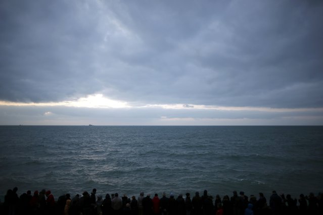 A crowd of people is seen in silhouette on the waterfront as people watch the incoming high tide in Saint Malo, western France, March 21, 2015. (Photo by Stephane Mahe/Reuters)