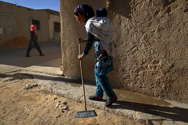 Aisha, 24, who is unemployed, carries her one-year-son as uses a broom outside her house at the impoverished Zhor neighborhood of Kasserine, where young people have been demonstrating for jobs since last week, January 29, 2016. Aisha receives a social support of two hundred and thirty dinars from the local government a month. “I lost all hope, nothing has changed in five years” Aisha said. (Photo by Zohra Bensemra/Reuters)