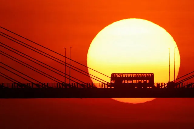 A double-decker bus passes through Ting Kau Bridge at sunset in Hong Kong, China on October 25, 2023. (Photo by Tyrone Siu/Reuters)
