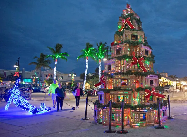 People walk past lobster traps stacked in the shape of a Christmas tree at the Historic Seaport in Key West, Florida, U.S., November 29, 2018. (Photo by Carol Tedesco/Florida Keys News Bureau/Handout via Reuters)