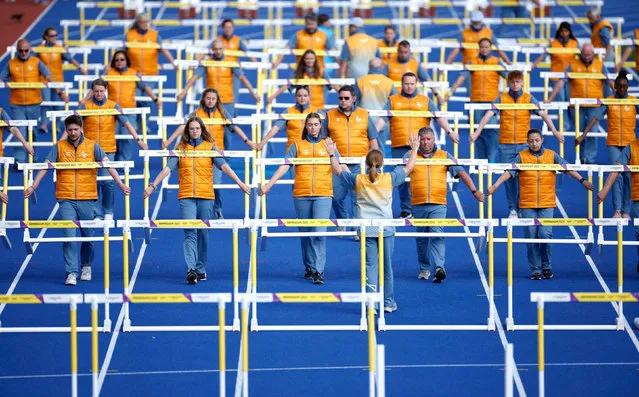 A view of the volunteers moving the hurdles for events at the Commonwealth Games in Birmingham, United Kingdom on August 5, 2022. (Photo by John Sibley/Reuters)