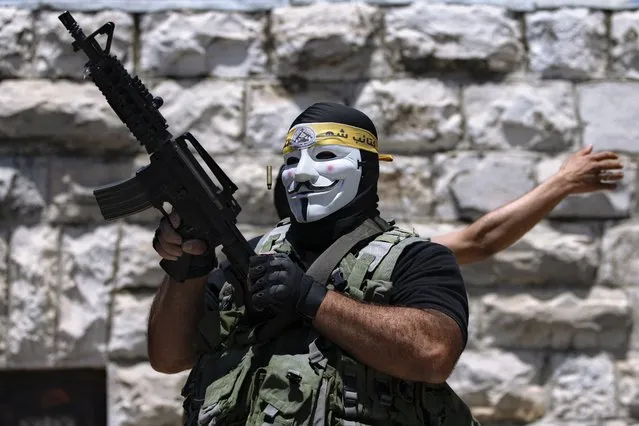 A masked Palestinian protester shoots in the air following the funeral of Mohammed al-Alami, 12, in the village of Beit Ummar, near the West Bank city of Hebron, Thursday, July 29, 2021. Villagers say the boy was fatally shot by Israeli troops while traveling with his father in a car. The Israeli military has launched an investigation into the shooting. (Photo by Majdi Mohammed/AP Photo)