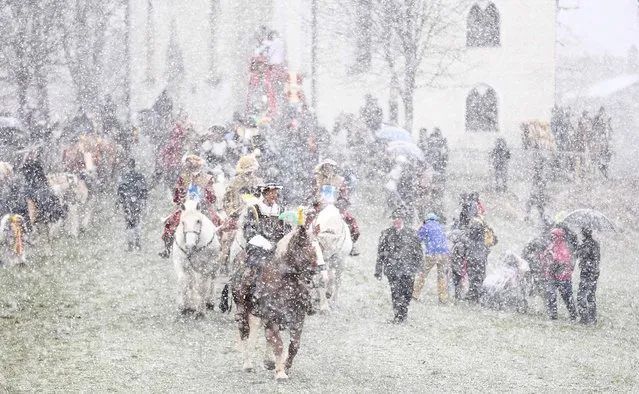 Local residents dressed in  historical costumes  ride  through heavy snowfall to get blessing for men and beast at the traditional Georg (St. George)  horse riding procession on Easter Monday in Traunstein, southern Germany, Monday, April 6, 2015. (Photo by Matthias Schrader/AP Photo)