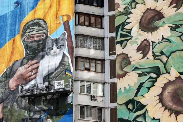 Artist Olena Noyna (L) works on a mural depicting a Ukrainian serviceman holding a cat, on a building in Kyiv, Ukraine, 03 October 2023, amid the Russian invasion. (Photo by Oleg Petrasyuk/EPA)