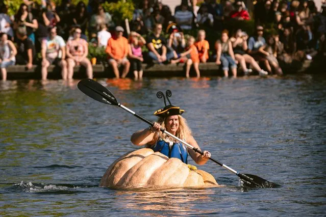 Emma Gray, of Tualatin, paddles to the finish line during the West Coast Giant Pumpkin Regatta in Tualatin, Oregon, on October 16, 2022. Since 2004, costumed characters in giant pumpkins compete in a series of races in Tualatin Lake. (Photo by Wesley Lapointe/AFP Photo)