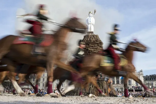 In this April 13, 2015 photo members of a guild ride around the “Boeoegg” on the Sechselaeuten place in Zurich, Switzerland. The Sechselaeuten (ringing of the six o'clock bells) is a traditional end of winter festival with a parade of guilds in historical uniforms on horseback and the burning of the Boeoegg, a symbolic snowman. The faster the Boeoegg explodes, the hotter the summer will be according to traditional weather rules. (Photo by Ennio Leanza/Keystone via AP)