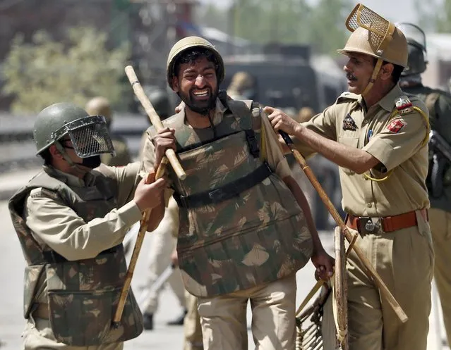 An Indian policeman (C) is being helped by colleagues after he was injured in a clash with Kashmiri protesters during a daylong protest strike in Narbal, north of Srinagar April 18, 2015. (Photo by Danish Ismail/Reuters)