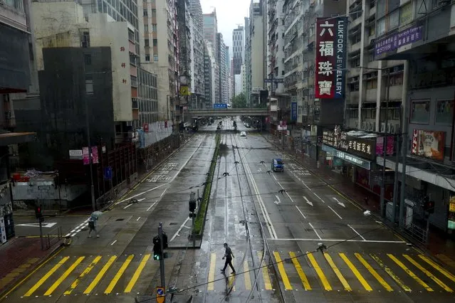 A man walks at an empty street as Typhoon Kompasu passes in Hong Kong Wednesday, October 13, 2021. Hong Kong suspended classes, stock market trading and government services as the typhoon passed south of the city Wednesday. (Photo by Vincent Yu/AP Photo)