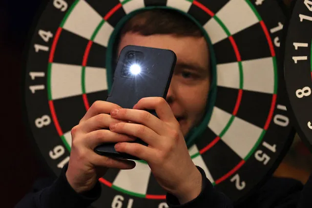 A fan takes a selfie photograph during Night 1 of the PDC Premier League, at the Utilita Arena in Cardiff, south Wales on February 1, 2024. (Photo by Adrian Dennis/AFP Photo)