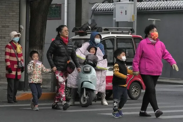 Residents, some wearing masks, cross a road in Beijing, China, Wednesday, October 20, 2021. (Photo by Ng Han Guan/AP Photo)