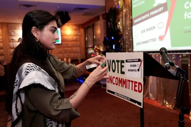 Activist Natalia Latif tapes a Vote Uncommitted sign on the speaker's podium during an uncommitted vote election night gathering as Democrats and Republicans hold their Michigan primary presidential election, in Dearborn, Michigan, U.S., February 27, 2024. (Photo by Rebecca Cook/Reuters)