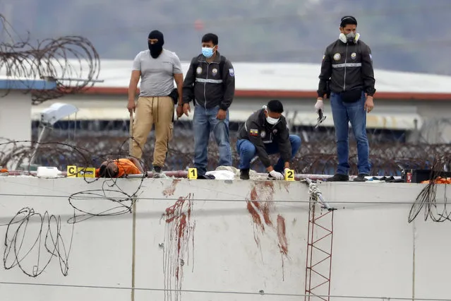 The body of a prisoner lies next to police on the roof of the Litoral penitentiary the morning after riots broke out inside the jail in Guayaquil, Ecuador, Saturday, November 13, 2021. A prolonged gunbattle between rival gangs inside Ecuador’s largest prison killed at least 68 inmates and wounded 25 on Saturday, while authorities said it took most of the day to regain control at the Litoral Penitentiary, which recently saw the country’s worst prison bloodbath. (Photo by Jose Sanchez/AP Photo)