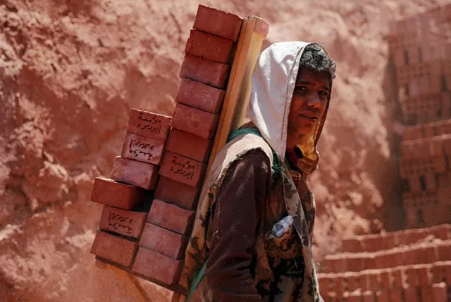 A labourer carries bricks while working at a traditional brick factory in Arab Mesad district of Helwan, northeast of Cairo, May 14, 2015. (Photo by Amr Abdallah Dalsh/Reuters)