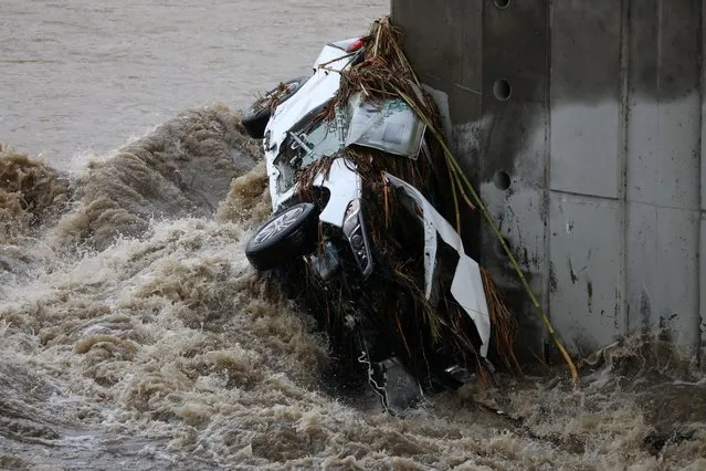 A car balances against a bridge trestle after entering the rising Los Angeles River as major storm hits California with rain and snow flooding the streets, in Los Angeles, California, U.S., December 14, 2021. (Photo by David Swanson/Reuters)