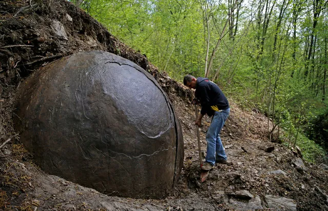 Suad Keserovic cleans a stone ball in Podubravlje village near Zavidovici, Bosnia and Herzegovina April 11, 2016. Keserovic claimed that the stone sphere is 3.30 meter in diameter and the estimated weight of it is about 35 tons. Hundreds of tourists from around the world have visited this stone. (Photo by Dado Ruvic/Reuters)