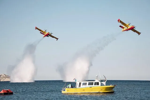 Two Canadair planes from the French Civil Protection, drop water the sea during an exercise at the entrance of the vieux port in Marseille on the first day of the Firemen congress, southern France on October 13, 2021. (Photo by Christophe Simon/AFP Photo)