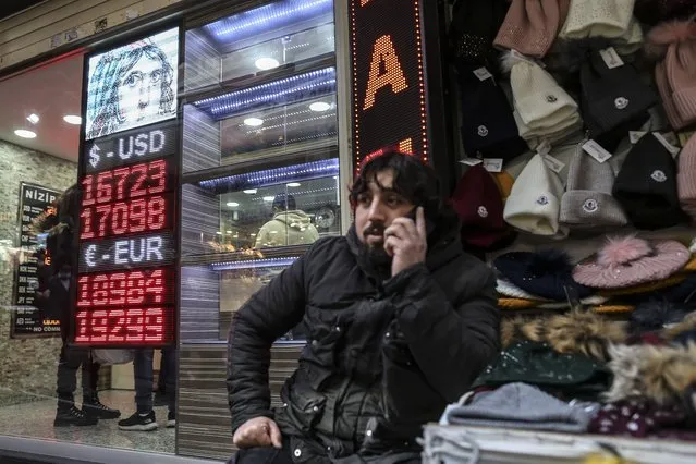 A man talks on the phone next to a currency exchange office in a commercial area in Eminonu district in Istanbul, Turkey, Friday, December 17, 2021. Turkey's currency has crashed to a new all-time low against the dollar on Friday, a day after the Central Bank again lowered a key interest rate despite surging consumer prices, in line with President Recep Tayyip Erdogan's unconventional economic policy. (Photo by Emrah Gurel/AP Photo)
