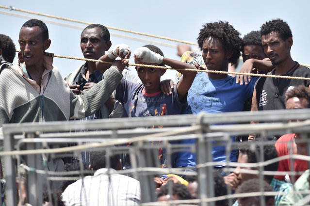 Migrants wait to be disembarked from the Irish Navy ship P31 L.E. Eithne at the Catania harbor, Italy, Tuesday, June 16, 2015. European Union nations failed to bridge differences Tuesday over an emergency plan to share the burden of the thousands of refugees crossing the Mediterranean, while on the French-Italian border, police in riot gear forcibly removed dozens of migrants. (AP Photo/Carmelo Imbesi)