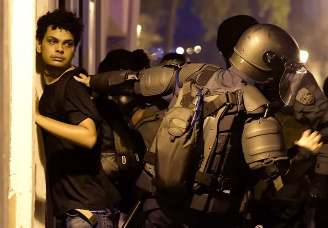 Police arrest a demonstrator during clashes in San Juan, Puerto Rico, Wednesday, July 17, 2019. Thousands of people marched to the governor's residence in San Juan on Wednesday chanting demands for Gov. Ricardo Rossello to resign after the leak of online chats that show him making misogynistic slurs and mocking his constituents. (Photo by Carlos Giusti/AP Photo)