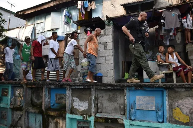 An agent (R) of Philippine Drug Enforcement Agency (PDEA) escorts suspects during a raid at an informal settlers' area inside a public cemetery in Manila on March 16, 2017. Philippine President Rodrigo Duterte in late January handed the drug war campaign over to the much smaller Drug Enforcement Agency, with support from the military, after an official investigation found members of police anti-drug officers kidnapped a South Korean businessman late last year, then murdered him at the national police headquarters as part of an extortion racket, but a month later President Duterte said he would recall police to fight his drug war. (Photo by Ted Aljibe/AFP Photo)
