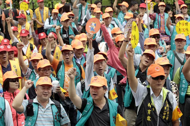 Taiwanese workers shout slogans during a May Day rally in Taipei, Taiwan, Sunday, May 1, 2016. Thousands of protesters from different labor groups protest on the street to ask for raising minimum wage and shorter working hours. (Photo by Chiang Ying-ying/AP Photo)