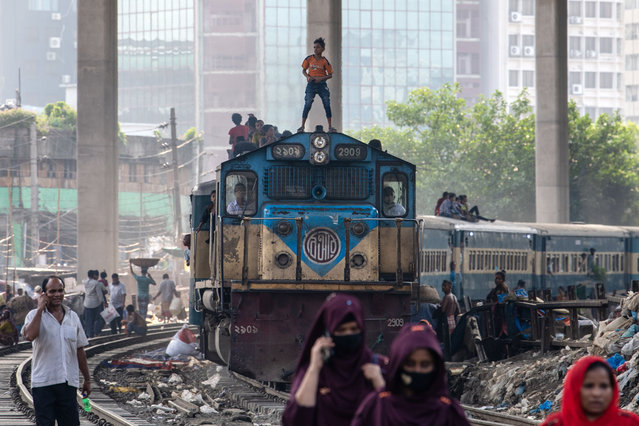 A boy is riding on top of a train as it is making its way through Kamlapur Railway Station in Dhaka, Bangladesh, on May 24, 2024. Many homeless children are living in railway stations and riding trains for fun. However, it is very dangerous, and there are calls for the authorities to prevent children from riding on train roofs. (Photo by Syed Mahamudur Rahman/NurPhoto)