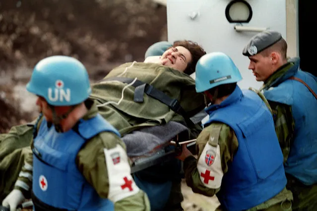 UN personnel carry one of the victim of marketplace at Sarajevo airport on February 06, 1994, to be flown out to American hospitals near Frankfurt or Zagreb. The day before a bomb exploded at main Sarajevoís marketplace, killing 68 people and wounding 200. It was the worst single atrocity in the 22-month old conflict between Bosnia's Serbs, Muslims and Croats. (Photo by Pascal Guyot/AFP Photo)