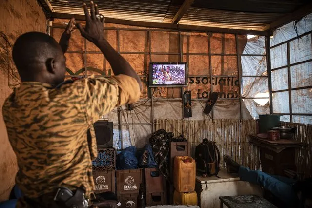 A soldier applauds the presidential inauguration of Junta leader Lt. Col. Paul Henri Sandaogo Damiba during his swearing-in ceremony broadcast on national television on Wednesday, February 16, 2022 in Ouagadougou, Burkina Faso. The inauguration ceremony, not open to the general public, was held at the constitutional court. (Photo by Sophie Garcia/AP Photo)