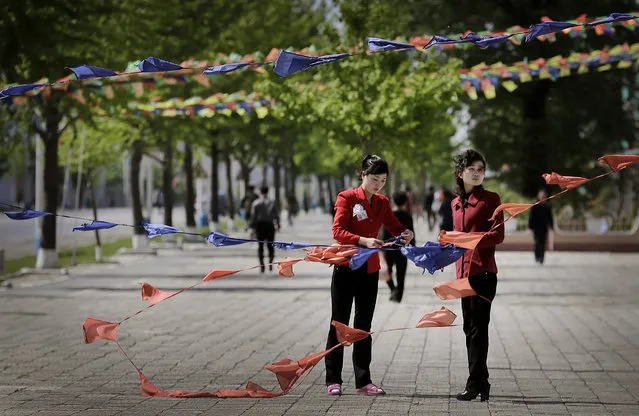 North Korean women tie flags as they decorate the streets in downtown Pyongyang, North Korea Saturday, May 7, 2016. North Korean leader Kim Jong Un hailed his country's recent nuclear test to uproarious applause as he convened the first full congress of its ruling party since 1980, an event intended to showcase the North's stability and unity in the face of tough international sanctions and deepening isolation. (Photo by Wong Maye-E/AP Photo)